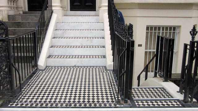 Traditional checkerboard tiling on a set of exterior steps of a large London town house. Marble step risers, and iron railings complete the period styling.
