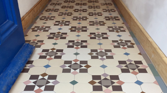 Unique patchwork floor tile design using 3 tones of white octagons, and contrasting colours for motif.