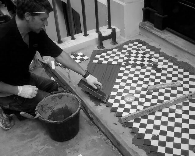Victorian floor tile specialist at work fitting sheeted black and white tiles