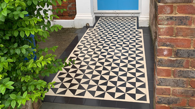 Exterior geometric black and white path composed of triangles leading to a blue front door.