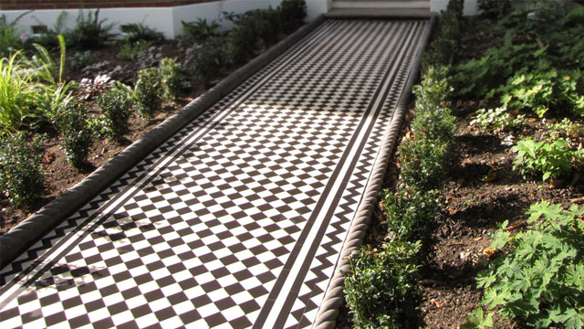 Classic Victorian black and white chequerboard exterior path tiles, framed with a zigzag border motif.