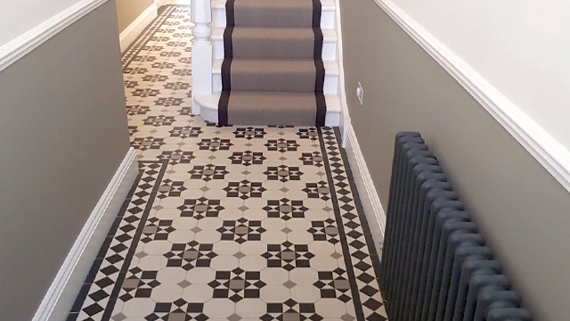 Narrow hallway painted in neutral tones featuring traditional Victorian floor tile design using octagons, squares and triangles.