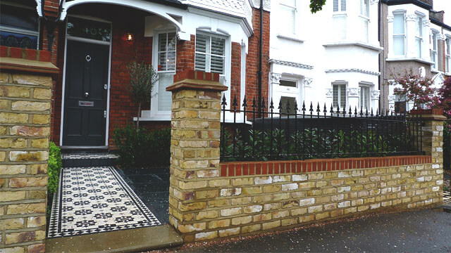 Traditional Victorian mosaic path tiles outside large semi-detached property with a 'London yellow' brick wall and metal railings.