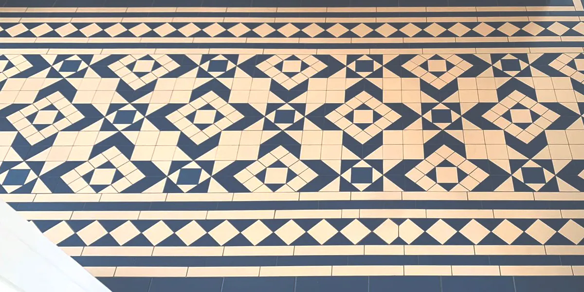 Complex geometric, monochrome tile pattern on hall floor. The design is framed with lines and diamond border.