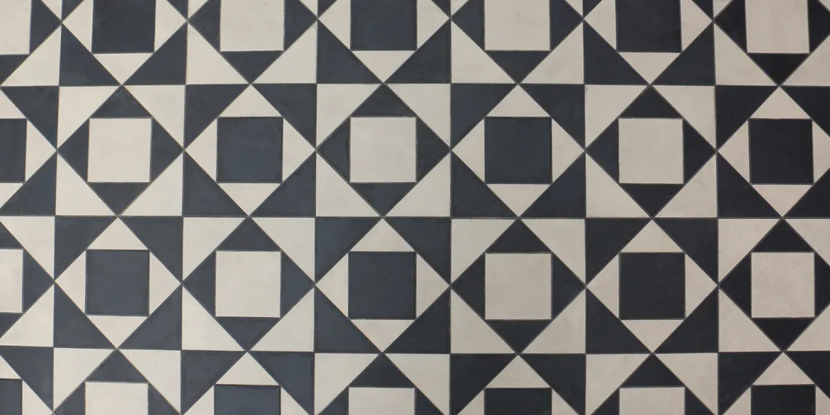 Birds-eye view of black and white geometric tiles in strong pattern of triangles and squares.