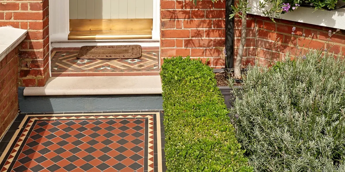 Traditional black and red path tiles, with yellow tiles in the border detail, alongside privet hedge.