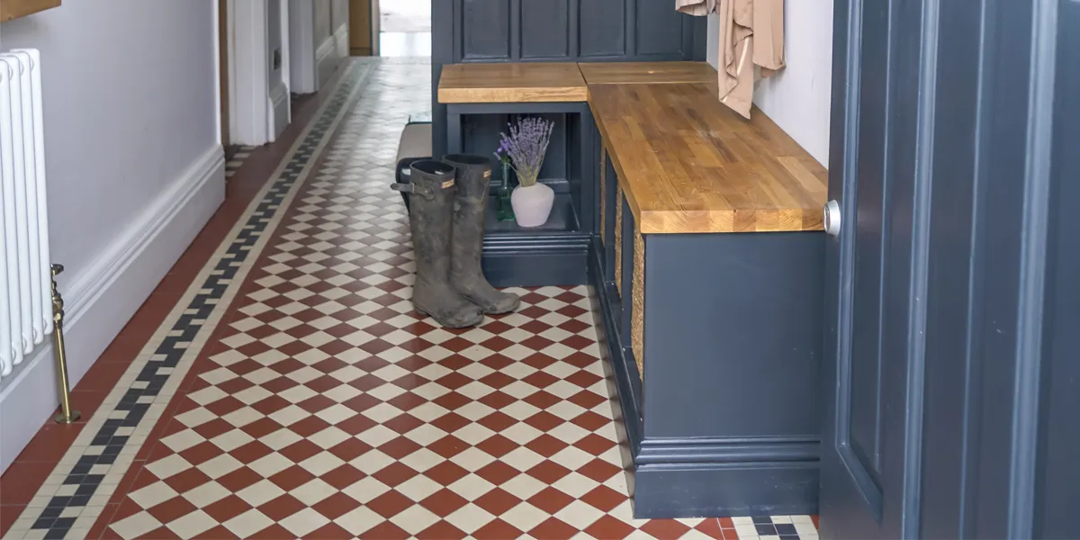 Red and white chequerboard tiles, with Greek key style border in black and white. Situated in hallway next to shoe cupboard and bench.