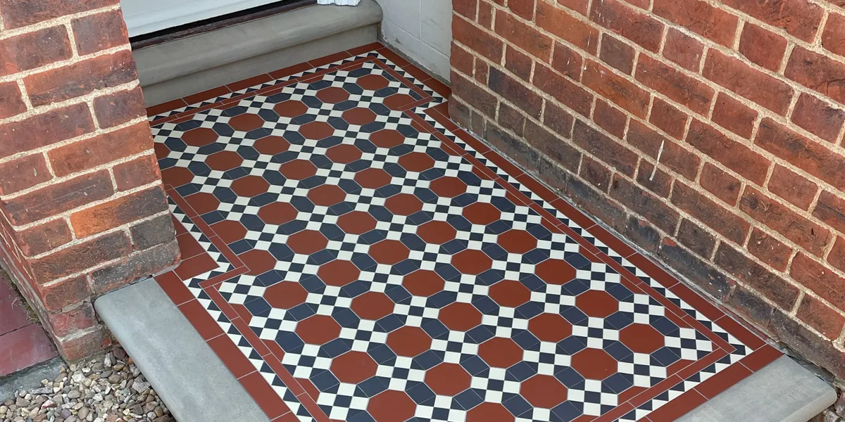 Red, black and white tiled path leading to an open porch area. The property has red bricks. A stone edging to the mosaic area matches the door step.