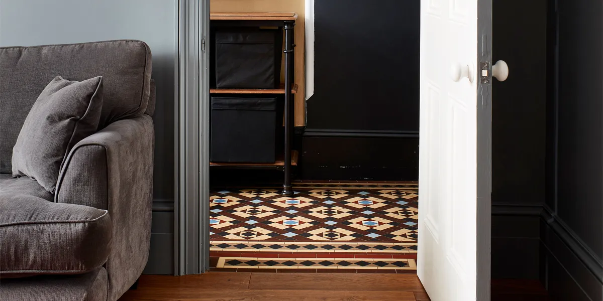 Brown and yellow Victorian hall floor tile design seen through living room.