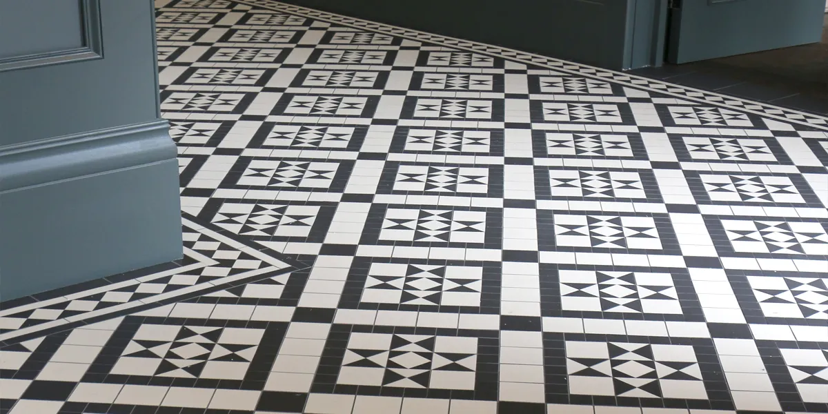 View of a Georgian-style mosaic hallway floor in contrasting black and white colours. The walls and doors are painted a grey-blue tone.