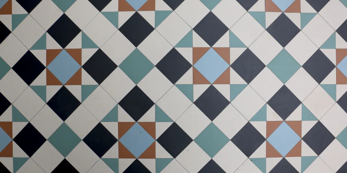 Close up view looking down at a colourful, geometric Victorian mosaic tile pattern.