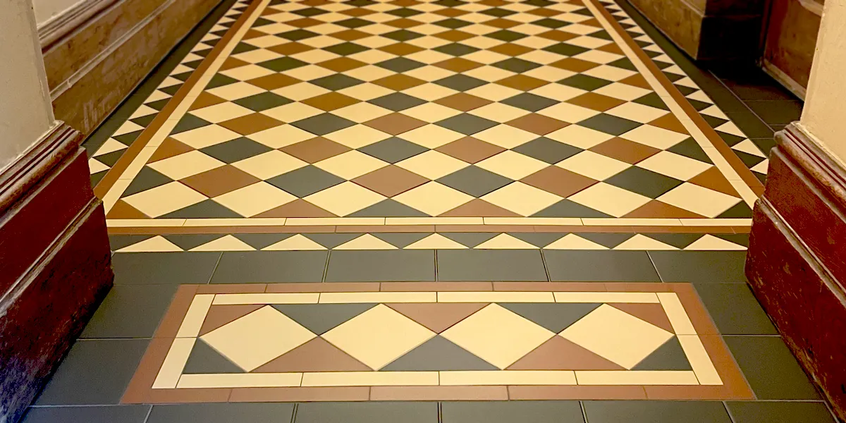 An Edwardian style tiled hallway floor in yellow, red and black tones. A deep threshold has another element of mosaic design to complement.