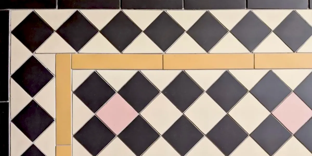 Close up view of black and white mosaic tiles, with a yellow rectangle frame in the border, and random pink tiles in the field.