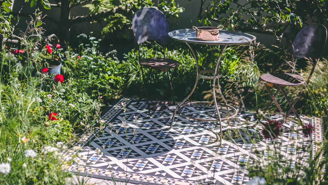Geometric mosaic tile pattern in black, white and blue as a garden patio feature.