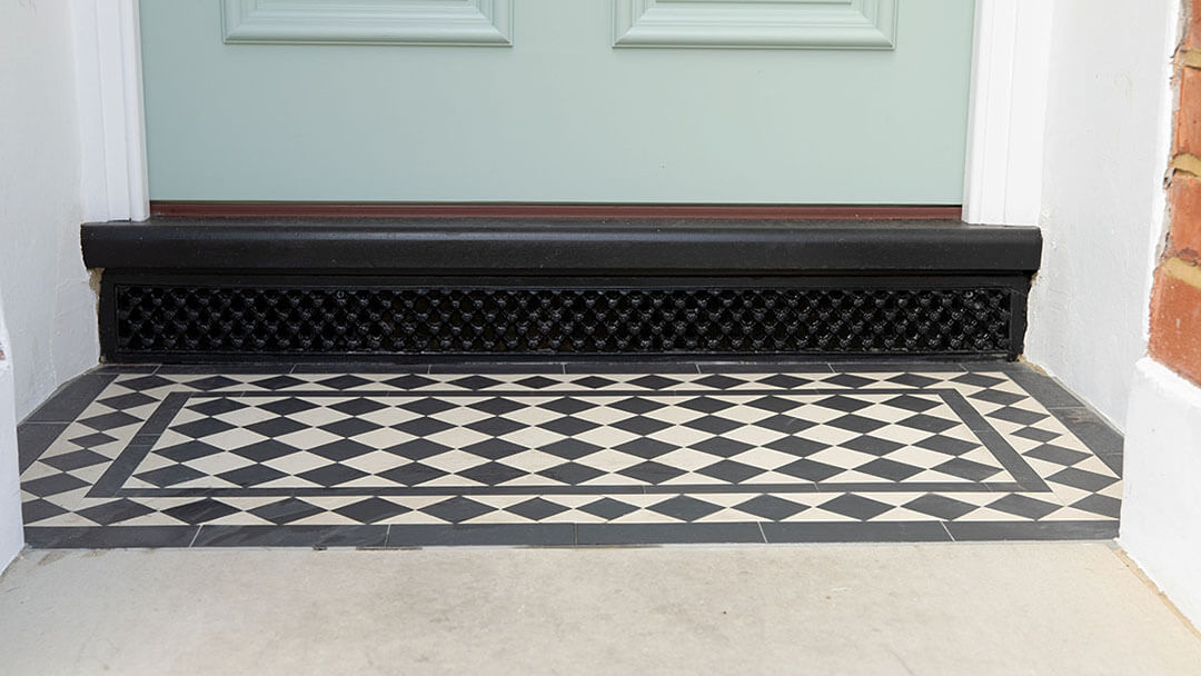 Reproduction Victorian Daisy Grate Ventilation Grille positioned under porch step.