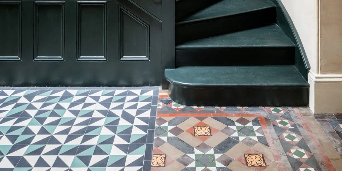 Random pattern triangular tiles on hallway floor alongside period tiling.
