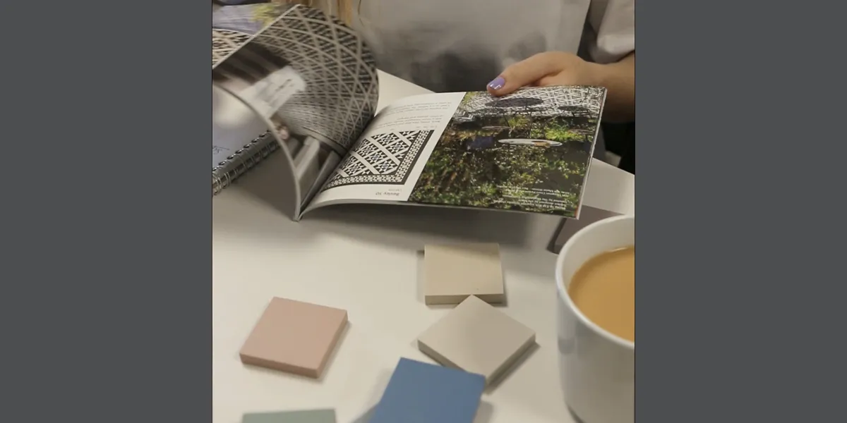 Browsing tile design catalogue with selection of sample tiles and cup of tea.