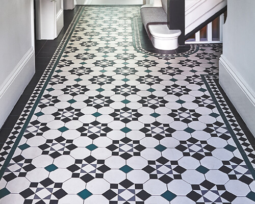Reproduction Victorian hall floor tiles, the Cornwall pattern in black, super white, dark green and slate. Border design follows curved base of staircase.