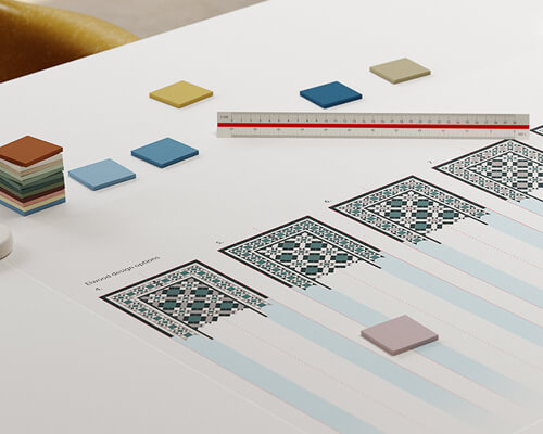Studio desk with print out of design variations, a ruler and sample colour tiles.