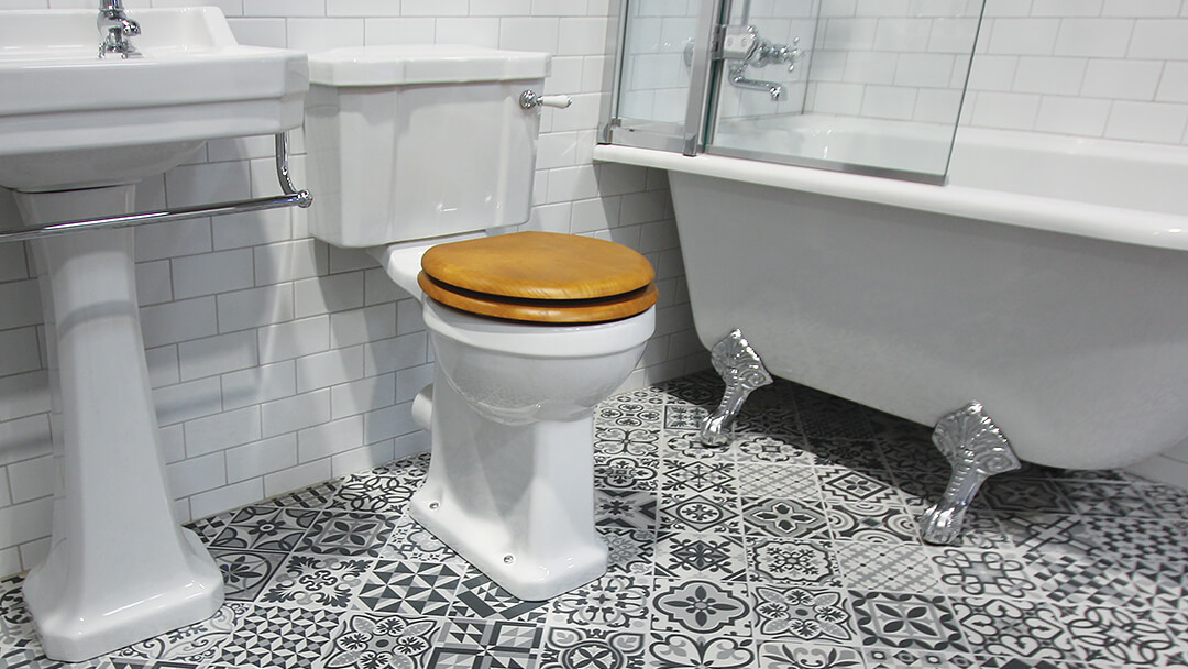 Traditional bathroom fittings with grey toned patchwork of printed encaustic style tiles.