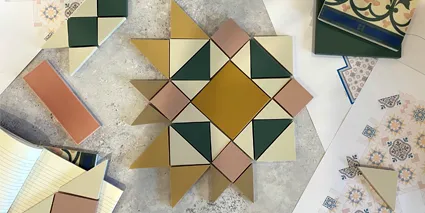Selection of different coloured and shaped tiles arranged on a desk, along with diagrams and note book.