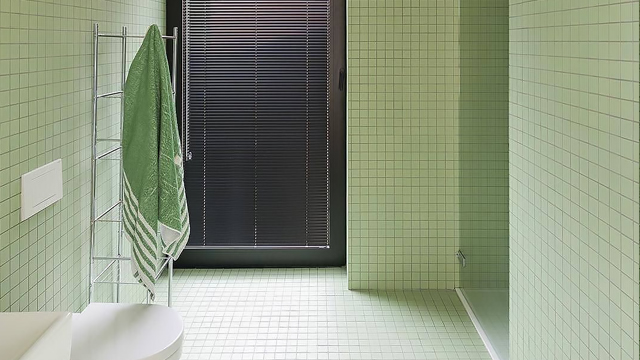 Pale green 50mm tiles on walls and floor of modern bathroom.