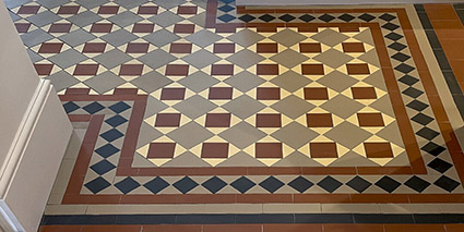 Restoration services. Red, buff, black and oatmeal coloured geometric floor tiles, restored and extended.