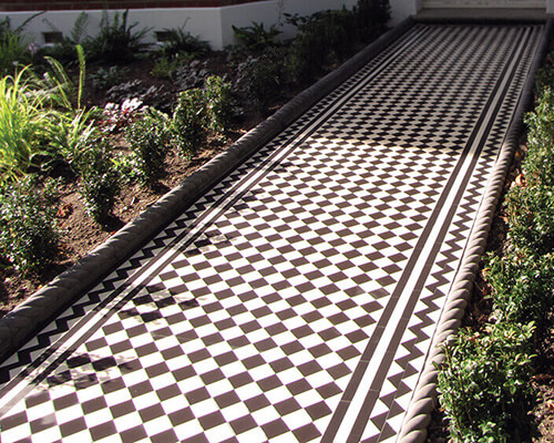 Classic black and white chequerboard path tiles with a zigzag border motif.